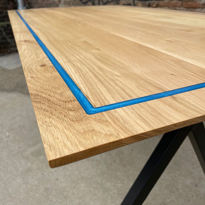 Eiken eettafel met gegoten blauwe epoxy rand.